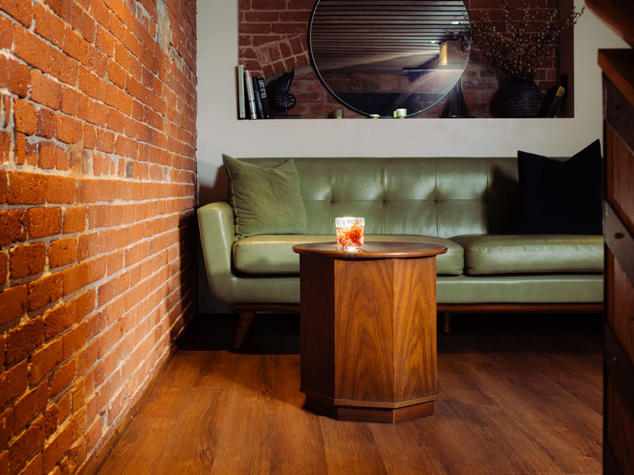 An Old Fashioned on a table in front of the upstairs loft's green leather sofa.