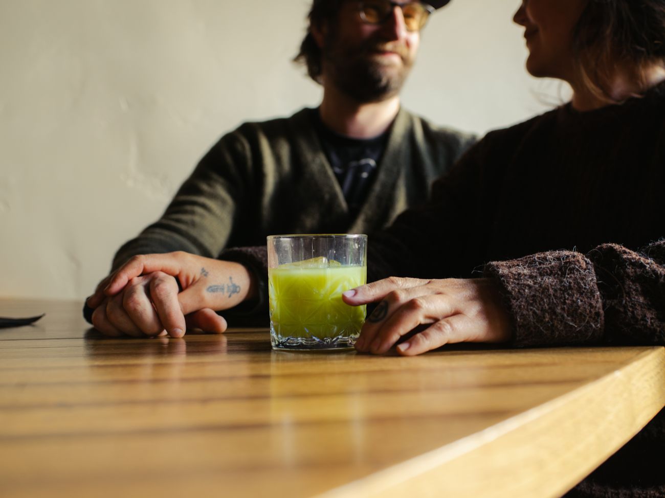 Two guests sharing a green cocktail at the bar.